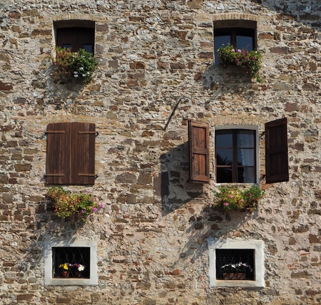 European rural house facade made of stone with flowers in every windowの写真素材