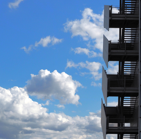 Stairway to the sky. Metal modern exterior staircase against blue sky with many cloudsの写真素材