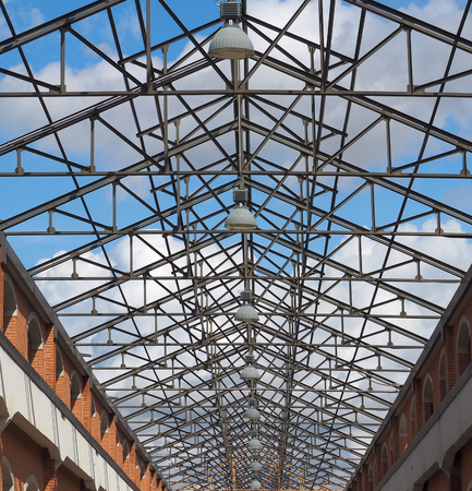 Row of lamps on the transparent roof of modern commercial building with blue cloudy skyの写真素材
