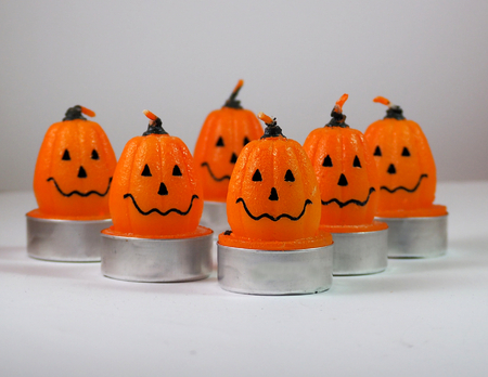 Halloween decorations. Smiling pumpkin shaped candles on a white surfaceの写真素材