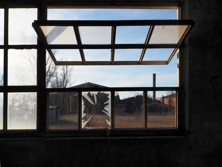 Old abandoned factory viewed through a half open windowの写真素材