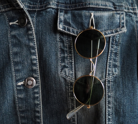 Trendy vintage circle sunglasses in a pocket of a denim jacketの写真素材