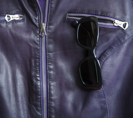 Black sunglasses for women in a pocket of violet leather jacketの写真素材
