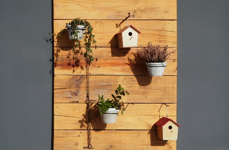 Outdoor garden wall decorations. Flower pots and bird houses on wooden panels. Gray wall backgroundの写真素材