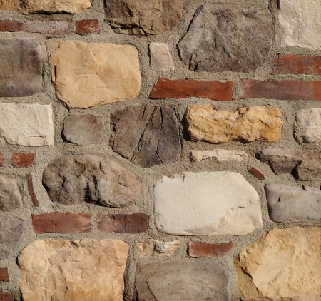 Rustic stone wall texture. The wall is made of red bricks, cement and natural stonesの写真素材