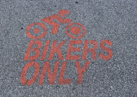 Motorcycle parking only sign, painted in red on asphalt with the silhouette of a motorcycle riding bikerの写真素材