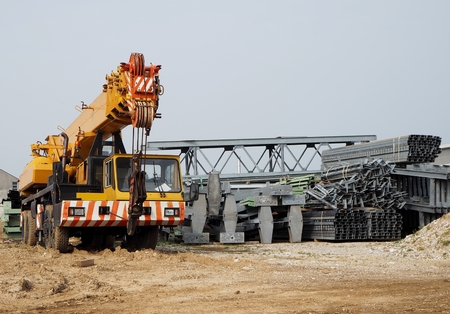 Front view of a telescopic crane next to scaffolding and construction of a new buildingの写真素材