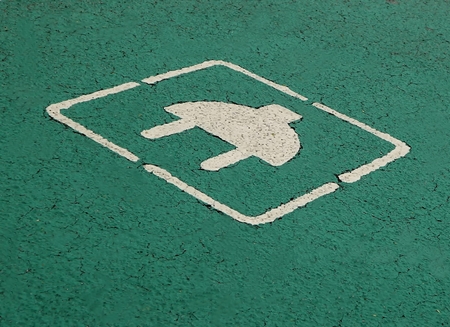 Electric car parking and charging White plug painted on green background in the asphaltの写真素材