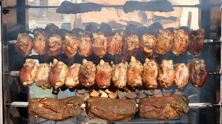 Grilled pork knuckles and shoulders on rotary spit, in a big barbecue.の写真素材