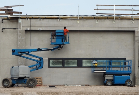 A worker on a cherry picker finishes On the right an aerial platform
