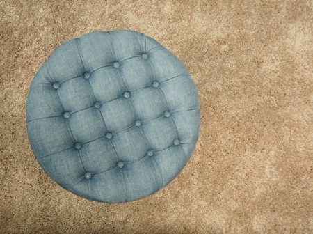 Blue pouf with buttons and squares. Brown carpet backgroundの写真素材