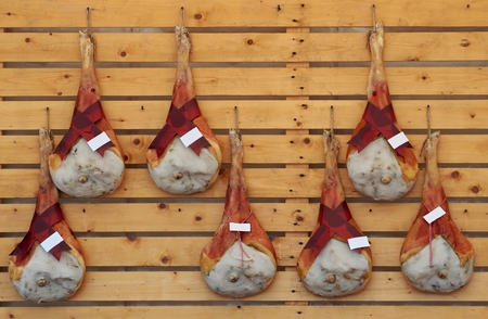 Leg hams of San Daniele ham, an excellent italian raw ham, hanging on a wooden wallの写真素材