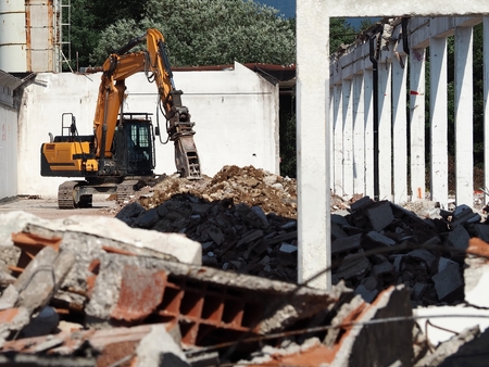 Excavator in a building under demolition, among rubble and dust, for an urban redevelopment.の写真素材
