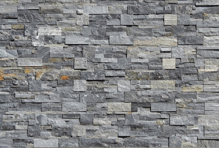 Gray stone wall cladding made of strips and square blocks stacked. Background and texture.