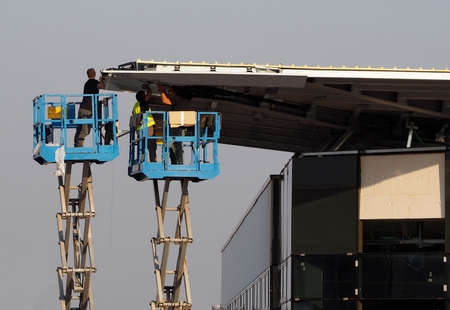 Workers on two cherry pickers, scissor lifts, finish the facade of a new building just buildの写真素材