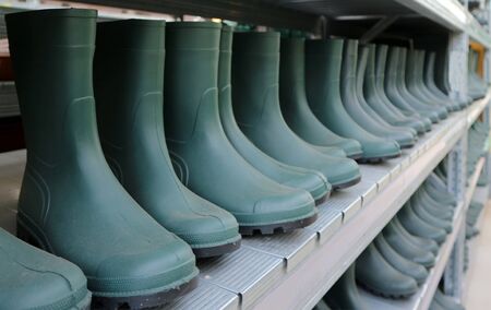Green rubber boots in a long row. Classic work shoes for farmers and gardeners.の写真素材