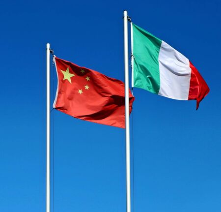 China and Italy flags waving together against blue sky.の写真素材