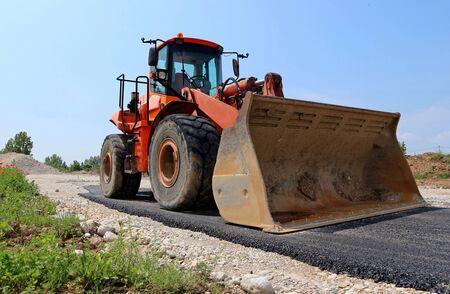 Large orange bulldozer on a half paved road at the construction site