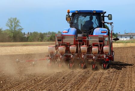 Tractor with a pneumatic seed drill machine on a freshly plowed field in summertimeの写真素材