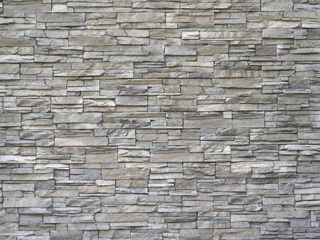 Stone cladding wall made of striped stacked slabs of natural gray rocks. Panels for exterior.