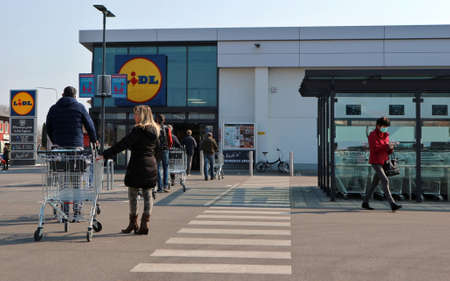 Udine, Italy. March 20,2020. People waiting to enter the supermarket Lidl maintain the safety distance provided by the government decree to block the spread of coronavirus. Entry is limited.のeditorial素材