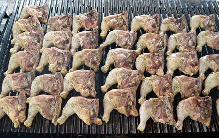 Lots of chicken leg quarters on a large grill for a summer barbecue. They have just been put over the grillの写真素材