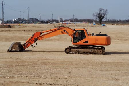 Excavator in a flat plain outside an area of ?? industrial development. Side viewの写真素材