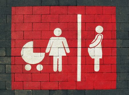 Woman only parking sign on asphalt painted of pink color. White symbol of a woman with stroller and pregnancy.の写真素材