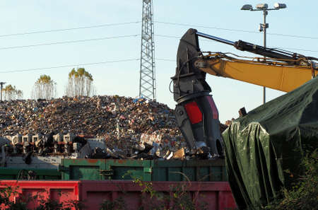 Excavator hydraulic magnetic boom at work among stacks of aluminum and ferrous materials scraps ready to be worked in the recycling factoryのeditorial素材
