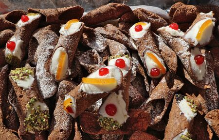 Heap of Sicilian Cannoli at the pastry shop. They are tube shaped shells of pastry dough, filled with cream, candied and pistachio.の写真素材