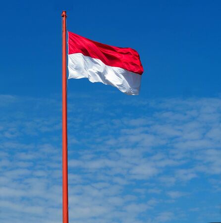 Indonesia flag against blue sky with clouds.の写真素材