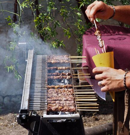 Cooking arrosticini, an Italian specialty of meat skewers, on their special grill.の写真素材