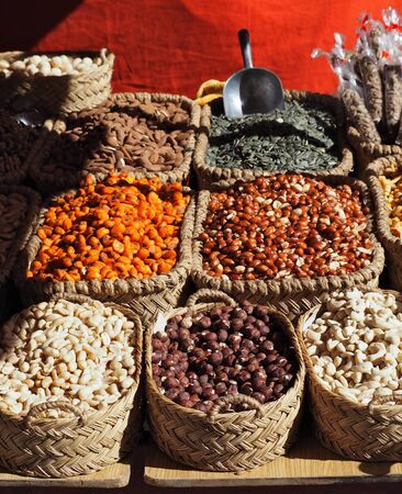 Hazelnuts, cashews, almonds, peanuts, toasted corn and sunflower seeds in straw baskets on the store shelfの写真素材