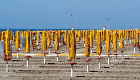 Empty beach on the Italian Adriatic Riviera, with closed umbrellas and folded sunbeds. Possible scenery next summer causes coronavirus epidemicの写真素材