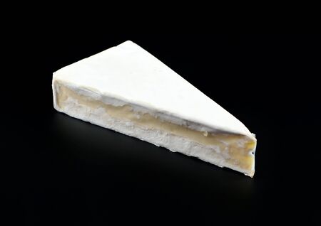 Slice of Brie, french soft cheese, on black backgroundの写真素材