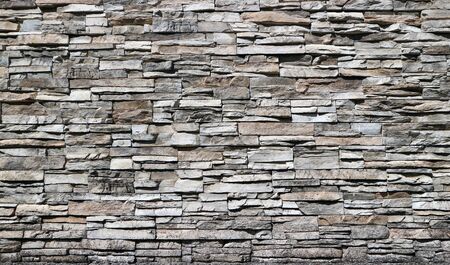 Stone cladding wall made of striped stacked bricks of natural brown and gray rocks.の写真素材