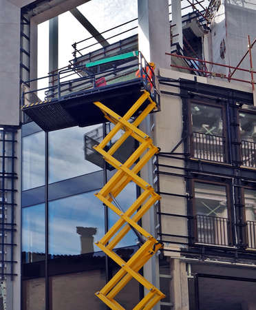 Scissor lift, a type of aerial platform, at work on a building facade under constructionの写真素材