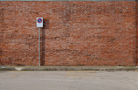 Grunge brick wall with a no stop road sign. A sidewalk and asphalt road in front. Background for copy spaceの写真素材