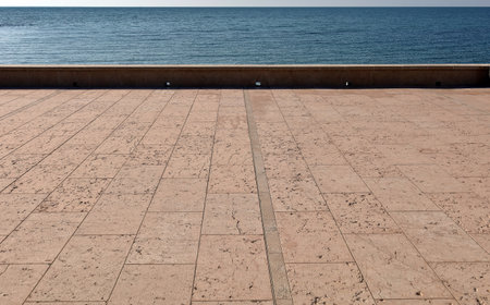 Pink granite tiled terrace with a fence and the sea on background. Copy space.の写真素材