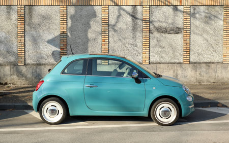 Udine, Italy. January 26, 2022. Light blue Fiat 500 hybrid with white rims. Side view with concrete and brick wall on background.のeditorial素材