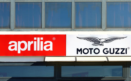 Pradamano, Italy. April 10, 2022. Aprilia and Moto Guzzi logos, both of them motorcycle brands of Piaggio group, on the facade of the official dealership.のeditorial素材