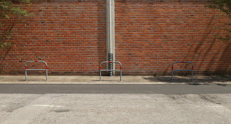 Exposed brick wall with metallic pedestrian barriers in sidewalk and asphalt street in front. Background for copy space.の写真素材