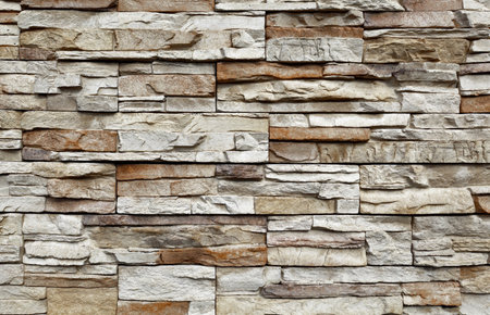 Stone cladding wall made of striped stacked slabs of gray and brown rocks. Panels for exterior. Backgrounds and textures.の写真素材