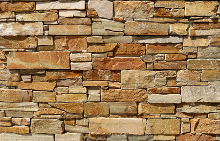 Stone wall with natural rock bricks of different shapes. Colors are shades of brown, white and gray. Backgrounds and texturesの写真素材