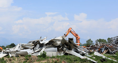 Large stack of aluminum and ferrous materials scrap in the recycling center. Orange excavator boom behind it.の写真素材
