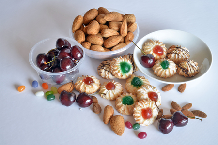 Sicilian biscuits made with almond paste and decorated with candied cherries. In the picture are the ingredients, almonds with shell, cherries and shelled almondsの写真素材