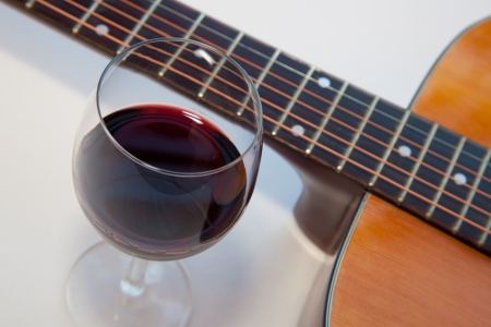 Glass of red wine and a part of acoustic guitar. White background with shadows.の写真素材