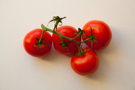 Four red tomatoes on green branch  White background の写真素材