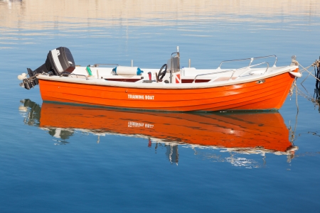 Orange boat moored in the harbor. Blue water. Diving flag. Inscription training boat. Reflected in the water.の写真素材
