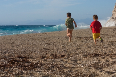 Two happy boys brothers run along the beach turned away backの写真素材